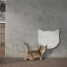 kleine rote Katze sitzt vor einem weißen Katzenkopf der an der Wand hängt